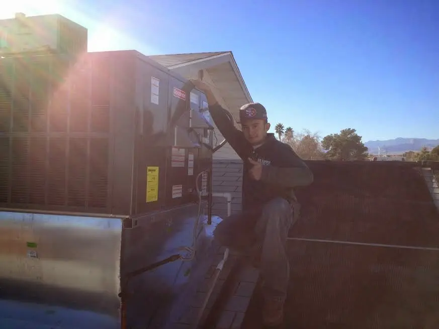 HVAC technician performing Heat Pump Repair on a rooftop unit in Grinnell